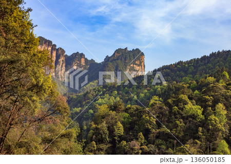 A mountain range with a clear blue sky and a few clouds 136050185
