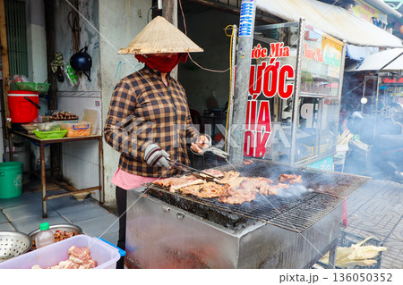 Iceland Phu Quoc Vietnam 5.7.2025. A woman wearing a mask is cooking meat on a grill Iceland Phu Quoc Vietnam 5.7.2025. A woman wearing a mask is cooking meat on a grill 136050352