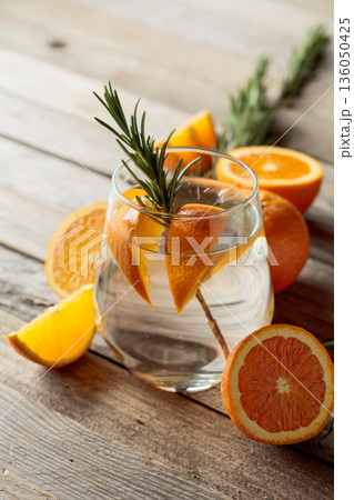 Gin tonic with ice, rosemary, and orange slices on an old wooden table. Gin tonic with ice, rosemary, and orange slices on an old wooden table. 136050425