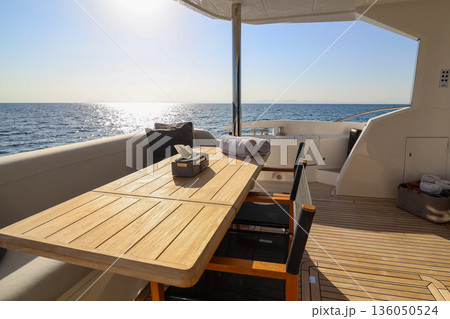 A wooden table with a chair and a towel on it is on a boat A wooden table with a chair and a towel on it is on a boat 136050524