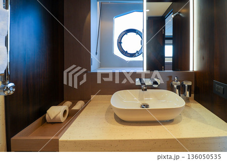 A bathroom with a white sink and a mirror in luxury boat 136050535