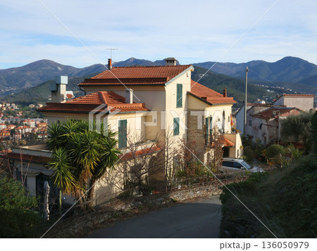 Traditional buildings, mountain houses. Nature and architecture of Liguria. Blue sky, clouds, and backdrop for design. 136050979