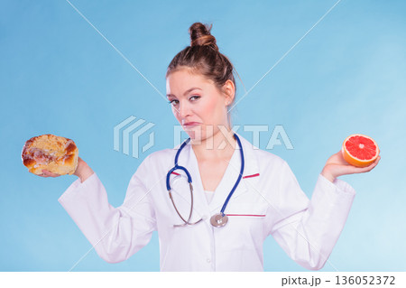 Disgusted dietitian with sweet bun and grapefruit. Disgusted dietitian with sweet bun and grapefruit. 136052372