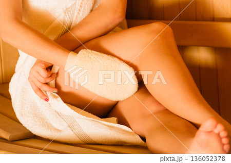 Closeup of woman in sauna with exfoliating glove. Closeup of woman in sauna with exfoliating glove. 136052378