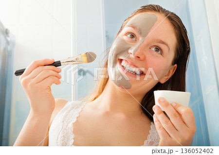 Woman applying mud facial mask 136052402