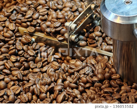 Freshly roasted coffee beans are being processed, showcasing their rich brown color and texture. image captures essence of coffee production, evoking sense of warmth and aroma Freshly roasted coffee beans are being processed, showcasing their rich brown color and texture. image captures essence of coffee production, evoking sense of warmth and aroma 136053582