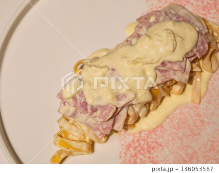 Creamy pasta dish with ham and cheese sauce on white plate, garnished with pink sprinkle. delicious and comforting meal perfect for any occasion Creamy pasta dish with ham and cheese sauce on white plate, garnished with pink sprinkle. delicious and comforting meal perfect for any occasion 136053587