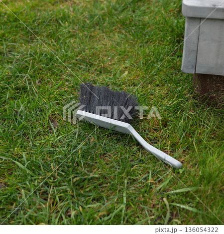 Gray broom on green grass near wooden bench in outdoor setting Gray broom on green grass near wooden bench in outdoor setting 136054322