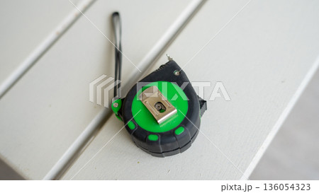 Green and black tape measure on white surface 136054323