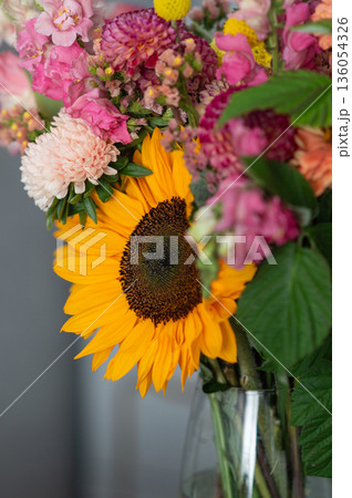 Vibrant sunflower bouquet with colorful assortment of pink and yellow blossoms in vase 136054326