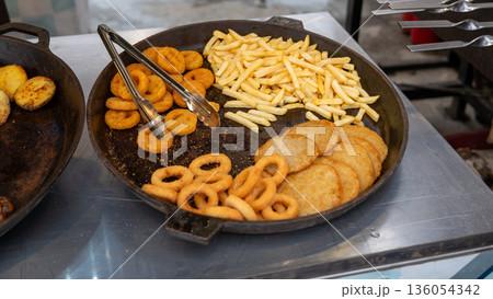 Variety of fried foods on display: onion rings, french fries, hash browns 136054342