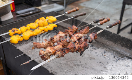 Grilled meat and vegetables on skewers cooking over charcoal Grilled meat and vegetables on skewers cooking over charcoal 136054343