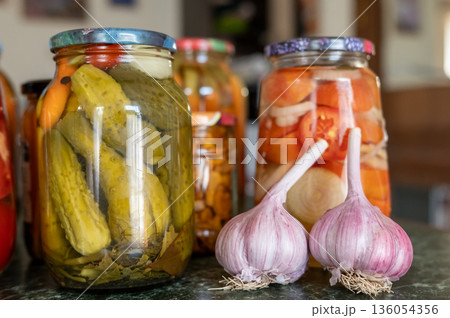 Assorted jars of pickled vegetables and garlic displayed on a kitchen counter. National Pickle Day Assorted jars of pickled vegetables and garlic displayed on a kitchen counter. National Pickle Day 136054356
