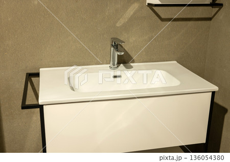 Modern bathroom vanity with white sink and chrome faucet on beige wall Modern bathroom vanity with white sink and chrome faucet on beige wall 136054380