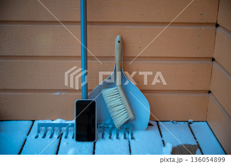 Winter cleaning tools with smartphone on snowy wooden terrace, minimal home lifestyle Winter cleaning tools with smartphone on snowy wooden terrace, minimal home lifestyle 136054899
