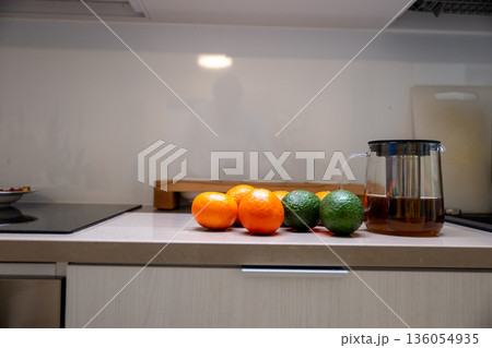 Fresh citrus fruit and glass teapot with hot tea on modern kitchen countertop Fresh citrus fruit and glass teapot with hot tea on modern kitchen countertop 136054935