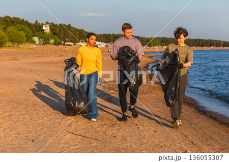 Earth day. Volunteers activists team collects garbage cleaning of beach coastal zone. Woman mans with trash in garbage bag on ocean shore. Environmental conservation coastal zone cleaning Earth day. Volunteers activists team collects garbage cleaning of beach coastal zone. Woman mans with trash in garbage bag on ocean shore. Environmental conservation coastal zone cleaning 136055307