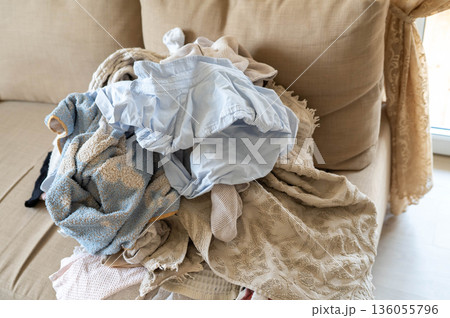 pile of washed un-ironed wrinkled linen on the sofa, household chores 136055796