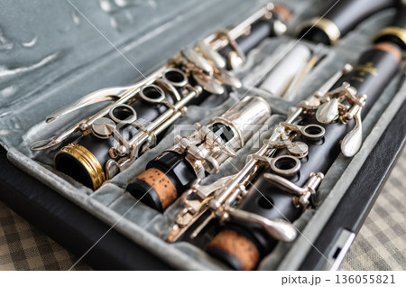 A black clarinet rests in an open case with a plush interior. The selective focus highlights its silver keys and sleek body, while the blurred background adds depth. A perfect shot for music and A black clarinet rests in an open case with a plush interior. The selective focus highlights its silver keys and sleek body, while the blurred background adds depth. A perfect shot for music and 136055821