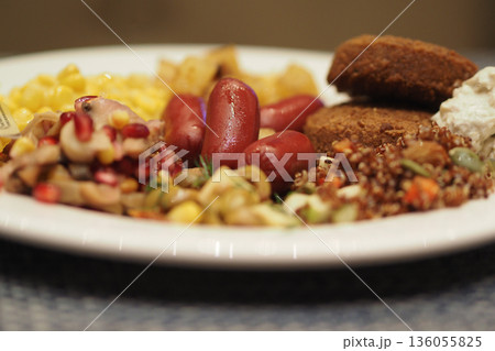A plate is filled with different foods like salads, sausage, and grains A plate is filled with different foods like salads, sausage, and grains 136055825