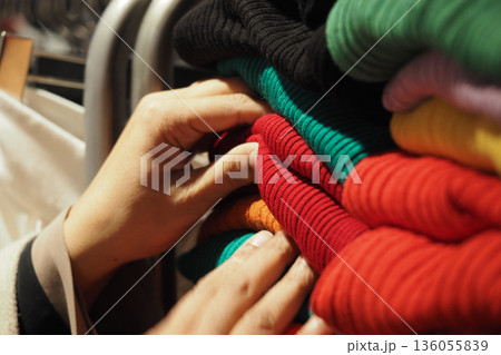 Sorting clothes in a store at evening time Sorting clothes in a store at evening time 136055839