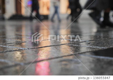 City street with rain reflecting people walking by 136055847