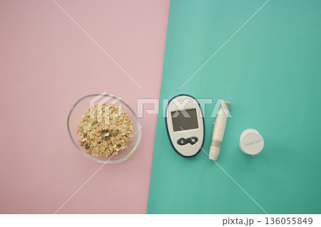 Oats on pink and blue surface next to diabetes testing kit 136055849