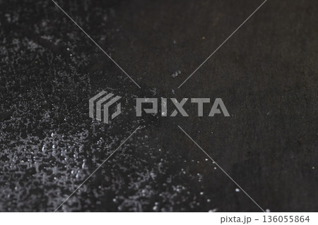 wet black uneven and embossed black slate for serving, covered with lots of water drops kitchen board made of black embossed slate, close up 136055864