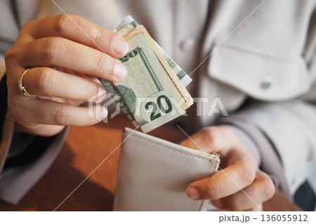 Counting cash in a wallet at a cafe in the afternoon Counting cash in a wallet at a cafe in the afternoon 136055912