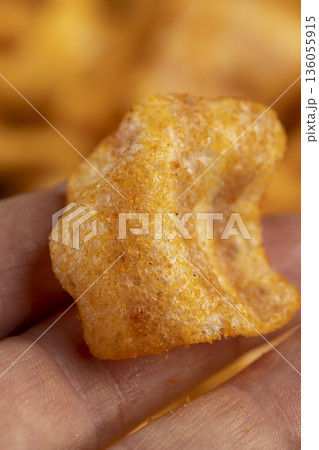 crispy mashed potato chips fried in a large amount of sunflower oil, sprinkled with red hot pepper , crispy delicious high-calorie chips with spices are scattered on the table 136055915