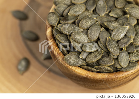 a large number of peeled large dried pumpkin seeds are lying on a wooden walnut board and in wooden dishes, a large number of healthy large pumpkin seeds without shells a large number of peeled large dried pumpkin seeds are lying on a wooden walnut board and in wooden dishes, a large number of healthy large pumpkin seeds without shells 136055920