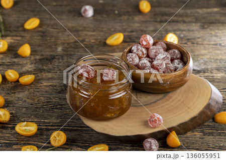 whole kumquat fruits in white powder, a glass jar with sweet orange jam on the table whole kumquat fruits in white powder, a glass jar with sweet orange jam on the table 136055951
