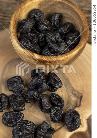 black soft dehydrated fruits of black plums, prunes on the kitchen table, black sweet seedless prunes scattered on the table black soft dehydrated fruits of black plums, prunes on the kitchen table, black sweet seedless prunes scattered on the table 136055954