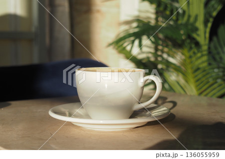 Warm cup of coffee on table near green plant 136055959