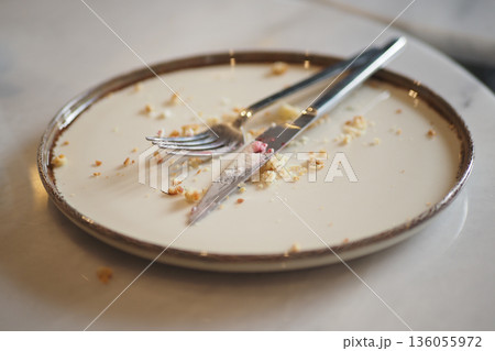 Empty plate with utensils and crumbs left after a meal 136055972