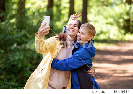Happy mother and son taking a selfie in a spring park, boy making faces and sticking out his tongue Happy mother and son taking a selfie in a spring park, boy making faces and sticking out his tongue 136056436