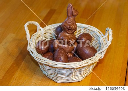 Basket with Easter eggs and Easter bunny on wooden table Basket with Easter eggs and Easter bunny on wooden table 136056608