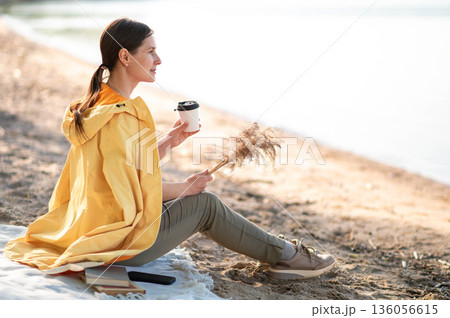 A young woman drinking coffee on the lake shore A young woman drinking coffee on the lake shore 136056615