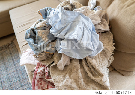 pile of washed un-ironed wrinkled linen on the sofa, household chores pile of washed un-ironed wrinkled linen on the sofa, household chores 136056718