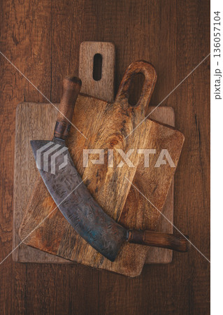 Old wooden cutting boards and a large curved knife on a rustic wooden table Old wooden cutting boards and a large curved knife on a rustic wooden table 136057104