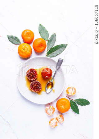 a plate with a spoonful of tangerine jam, fresh tangerines, on a marble table, top view, 136057118