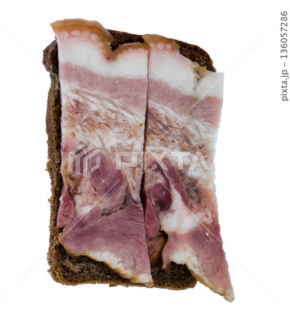 Slice of bacon with meat layers and a slice of black bread on white background isolated 136057286