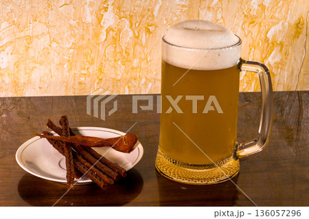 Glass with amazing beer and a plate with a snack on the table Glass with amazing beer and a plate with a snack on the table 136057296