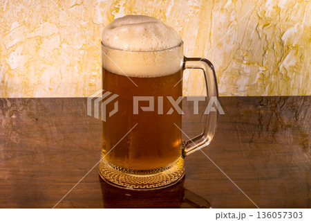 Glass with amazing beer and foam on top of the table 136057303