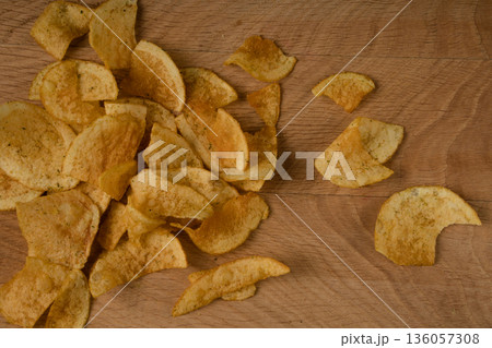 Appetizing potato chips are scattered on a wooden board Appetizing potato chips are scattered on a wooden board 136057308