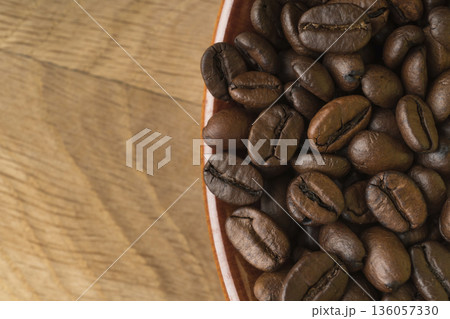 Ripe and roasted, coffee beans, in a cup on the background of a wooden board Ripe and roasted, coffee beans, in a cup on the background of a wooden board 136057330