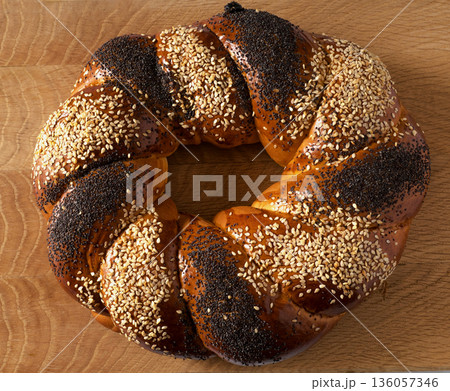 A sweet Slavic bun, made in the shape of a ring, called Kalach, on a wooden board A sweet Slavic bun, made in the shape of a ring, called Kalach, on a wooden board 136057346