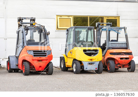 Colorful forklifts rest side by side in a quiet industrial yard on a sunny day 136057630