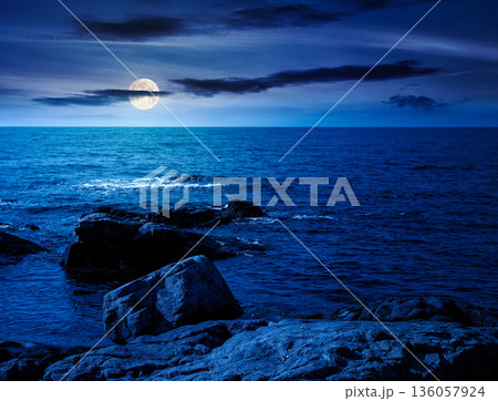 rocky shore of the sea coast under blue sky at night. beautiful view of coastal scene in full moon light. resort scenery during vacation season in summer. backdrop for fiction art or mystery concepts rocky shore of the sea coast under blue sky at night. beautiful view of coastal scene in full moon light. resort scenery during vacation season in summer. backdrop for fiction art or mystery concepts 136057924