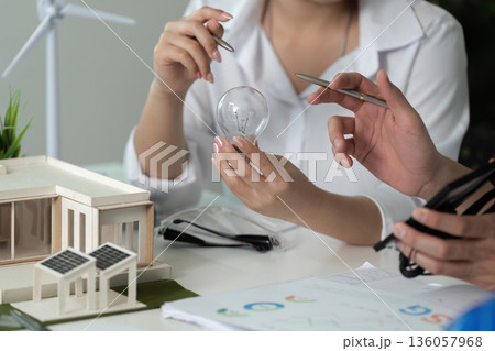Two people are working on a project, one of them holding a light bulb Two people are working on a project, one of them holding a light bulb 136057968